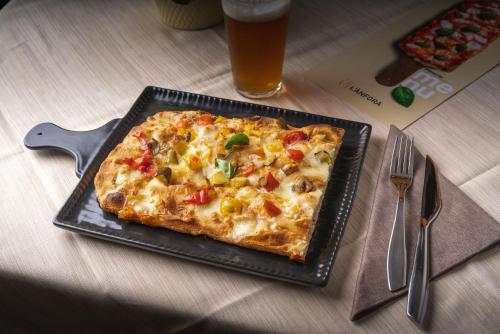a pizza on a plate on a table with a glass of beer at L'Anfora in Deruta