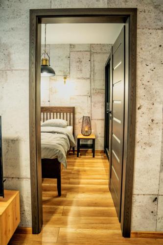 a bedroom with a bed and a wooden floor at Loftowy Zakątek in Leszno