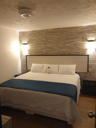 a bedroom with a large bed with a brick wall at Hotel Don Carlos in Morelia