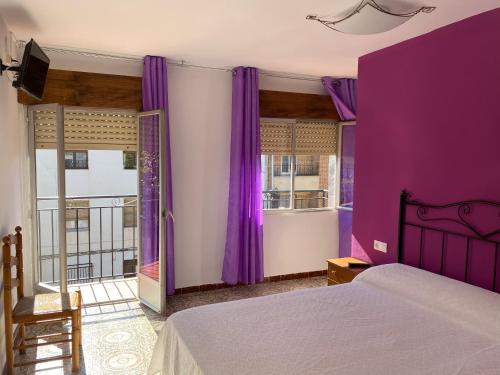 Dormitorio púrpura con cama y balcón en Hostal Grimaldos, en Riópar