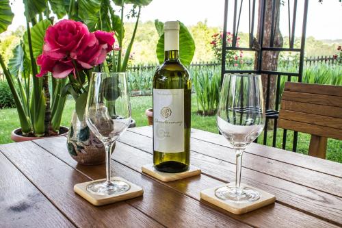 una botella de vino en una mesa de madera con 2 copas de vino en Rooms Marijana Obrovac, en Slunj