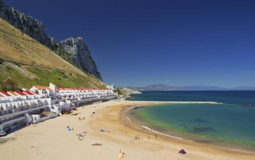 a beach with people on the sand and the water at Luxury Ocean Spa Plaza Private Large 1 bed apartment in Gibraltar