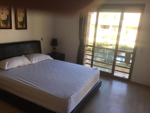 - une chambre avec un grand lit et un balcon dans l'établissement Apartement Golf Resort, à Sidi Bouqnadel