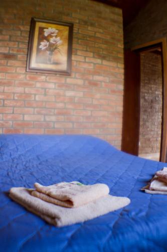 a blue bed with two towels on top of it at CHALÉ NATIVO R Júlio Miranda nº 06 in Conceição da Ibitipoca