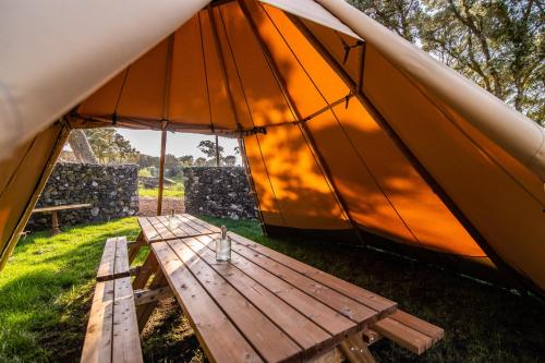a tent with a wooden table in the grass at Azor'Oasis in Calhetas