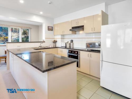 a kitchen with white cabinets and a black counter top at Snowman 2 in Thredbo