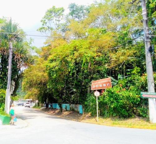 a person walking down a street with a street sign at SUITES E CHALES PRIVADOS Rock's&Rose's home in Camburi