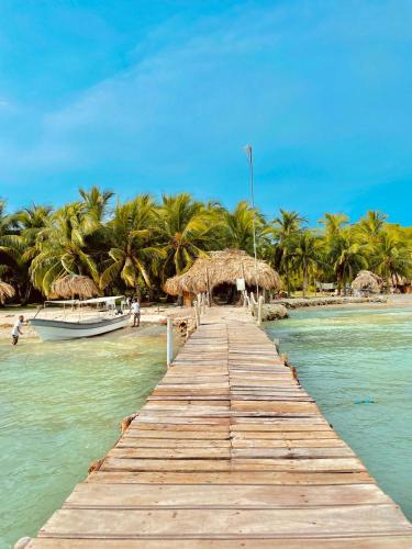 a wooden pier leading to a beach with a boat at Mistica Island Hostel - Isla Palma in Isla Palma