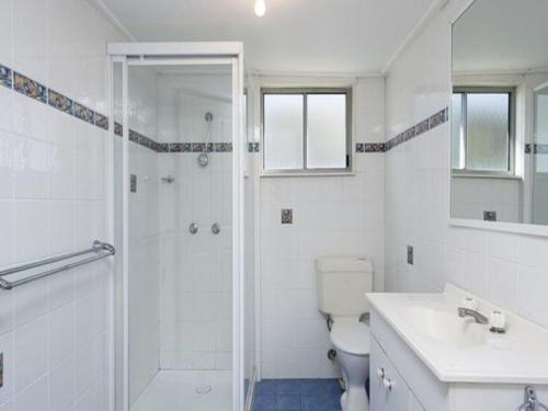 a white bathroom with a shower and a toilet at Stillwater large cottage across from the water sleeping 13 in Nelson Bay