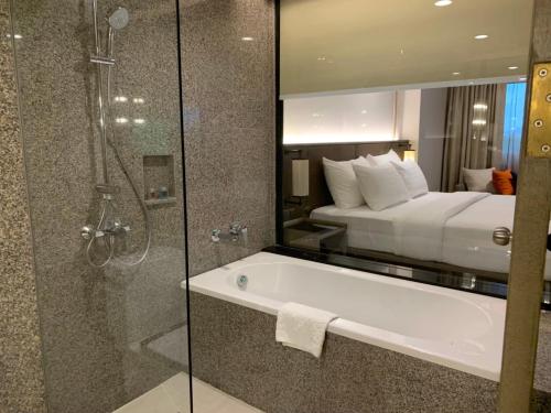 a bathroom with a shower and a tub and a bed at Sima Thani Hotel in Nakhon Ratchasima
