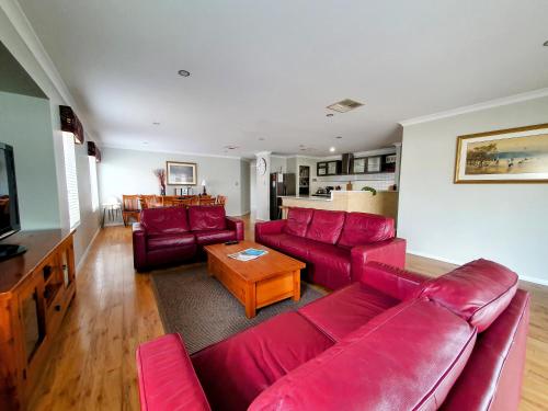 a living room with a red couch and a table at Hideaway By the Bay in Busselton