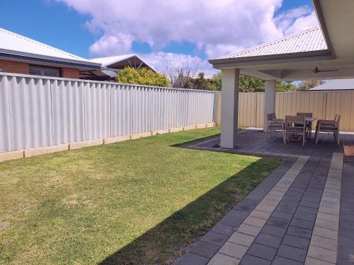 a patio with a table and chairs and a fence at Hideaway By the Bay in Busselton