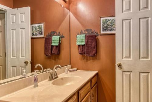 a bathroom with a sink and a mirror at Sunset Ridge Cabin - A Romantic Smoky Mountain Escape or Family Getaway - behind Dollywood, large game room, jacuzzi tub, fire pit, large wrap-around deck, and more in Pigeon Forge