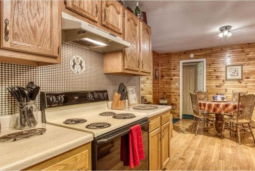 a kitchen with wooden cabinets and a stove top oven at Sunset Ridge Cabin - A Romantic Smoky Mountain Escape or Family Getaway - behind Dollywood, large game room, jacuzzi tub, fire pit, large wrap-around deck, and more in Pigeon Forge