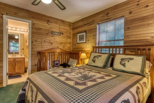 a bedroom with a bed in a room with wooden walls at Sunset Ridge Cabin - A Romantic Smoky Mountain Escape or Family Getaway - behind Dollywood, large game room, jacuzzi tub, fire pit, large wrap-around deck, and more in Pigeon Forge
