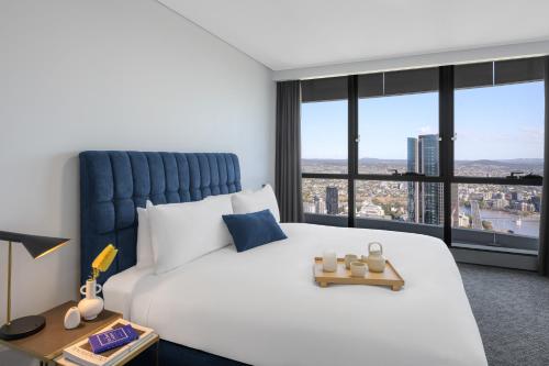 a bedroom with a large white bed and large windows at Meriton Suites Herschel Street, Brisbane in Brisbane