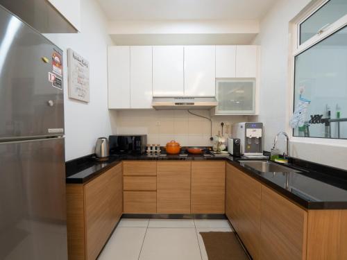 a kitchen with white cabinets and a stainless steel refrigerator at Seaview condo near RF Mall, Food Court & Free Netflix in Johor Bahru