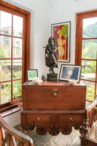 a dresser with a statue on it in a room with windows at Gruhaya Boutique Villa in Kandy