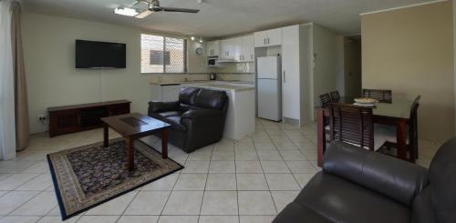 a living room filled with furniture and a refrigerator at Merrima Court Holidays in Caloundra