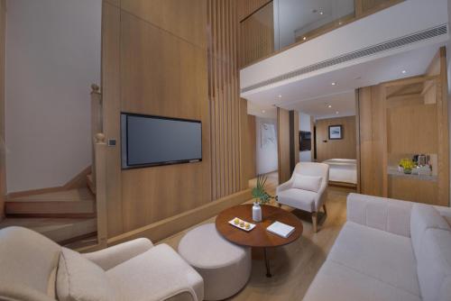 a living room with a couch and a tv on a wall at voco Thousand Island Lake, an IHG Hotel in Chun'an