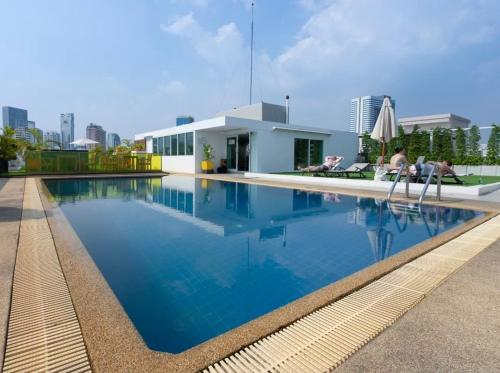 una piscina de agua azul frente a un edificio en The Tivoli Hotel en Bangkok