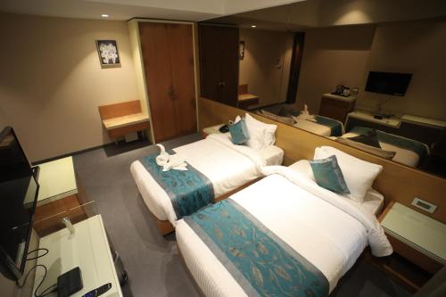 a hotel room with two beds and a television at The Byke Delotel in Mumbai