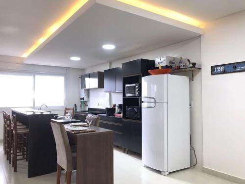 a kitchen with a white refrigerator and a table at RESIDENCIAL Montevidéu 805 in Osório