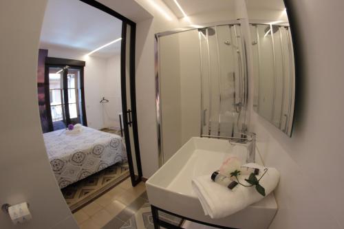 een badkamer met een wastafel, een spiegel en een bed bij FP HOTELs in Alcalá de Henares