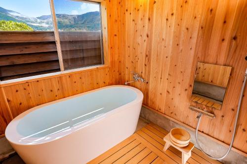 baño de madera con bañera y ventana en Cominka Yufuin en Yufuin
