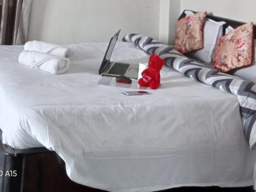 a red stuffed animal sitting on a bed with a laptop at Madys view -Aaple Ghar in Darjeeling