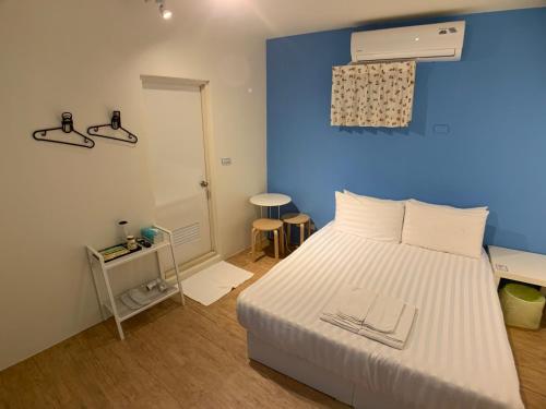 a bedroom with a white bed and a blue wall at Lazy bone in Hsinchu City