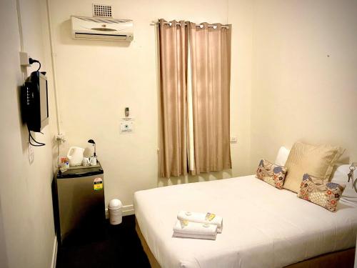 MilesWindsor Hotel Miles的小房间,配有带毛巾的床