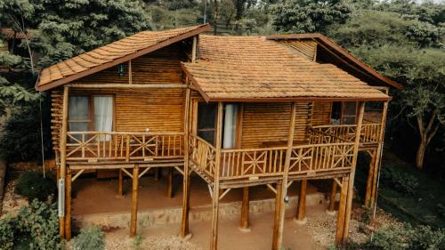 a wooden house with a large deck in the woods at Vintage Cottage in Rwamagana