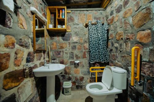 a stone bathroom with a toilet and a sink at Vintage Cottage in Rwamagana