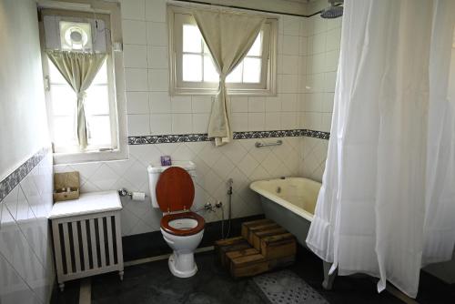 a bathroom with a toilet and a bath tub at Tumsong Tea Retreat in Darjeeling