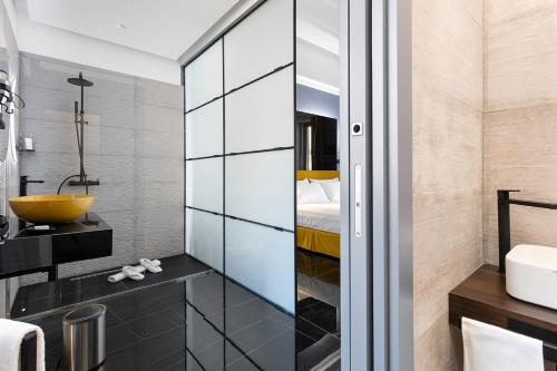 a bathroom with a glass partition with a sink and a bed at Hotel Poerio 25 Boutique Stay in Naples