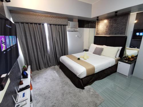 a hotel room with a bed and a television at Avida Davao by davaobnb & Lemonique Homes in Davao City