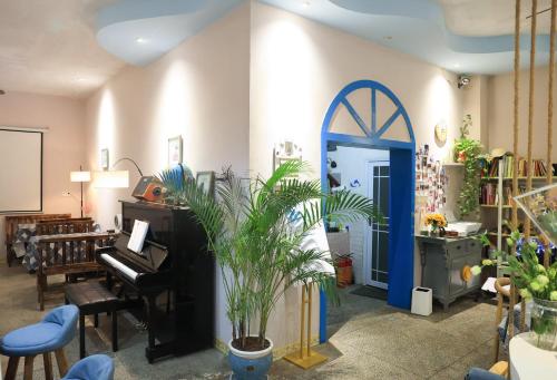 a living room with a piano and a potted plant at Murphy Youth Hostel Guilin桂林北站莫非青年旅舍 in Guilin