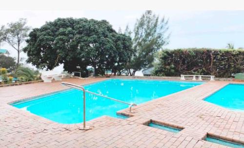 a large swimming pool with blue water on a brick floor at M8 Umdloti Holiday Resort in Umdloti