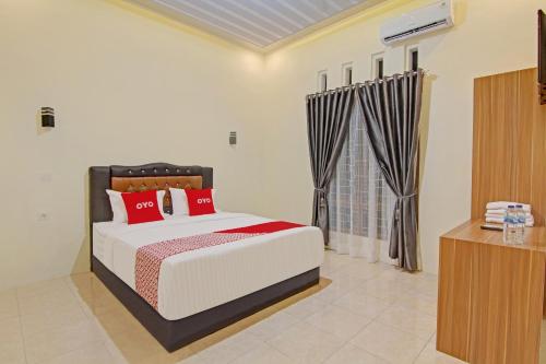 a bedroom with a large bed with red pillows at Super OYO Capital O 90643 Suri Guest House Syariah in Padang