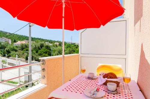 a table with a red umbrella on a balcony at Guesthouse Somnium in Cavtat