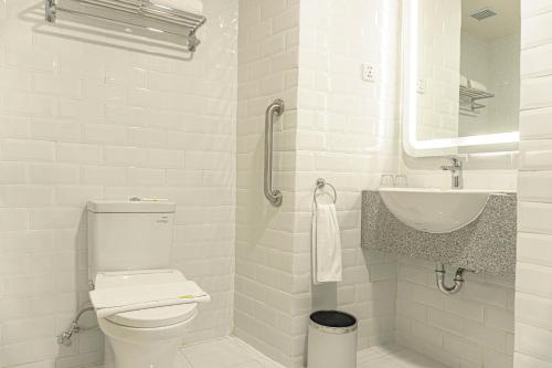 a white bathroom with a toilet and a sink at Yello Hotel Jambi in Jambi