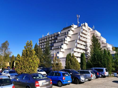 un estacionamiento con autos estacionados frente a un edificio en Hotel Montana - Covasna en Covasna