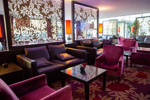 a living room with couches and chairs and a table at Clarion Paris CDG Airport in Roissy-en-France