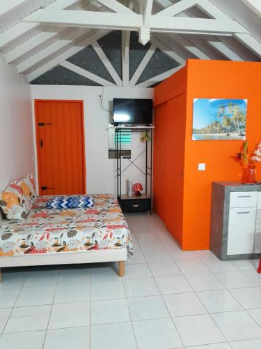 a bedroom with orange and white walls and a bed at Bungalow charmant à Petit-Bourg avec jardin privatif in Petit-Bourg