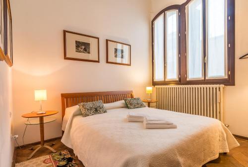 Un dormitorio con una cama grande con dos ventanas. en Red House close to @Accademia Bridge, en Venecia