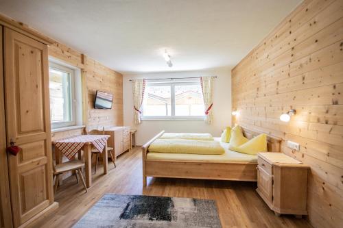 a bedroom with a bed and a wooden wall at Alpengasthof Eppensteiner in Navis