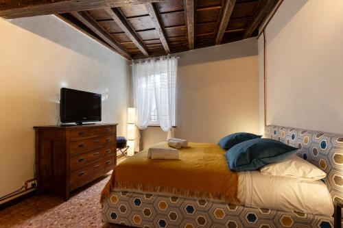 a bedroom with a bed with a television and a dresser at Maison di Lidia - Smart Holiday in Mantova