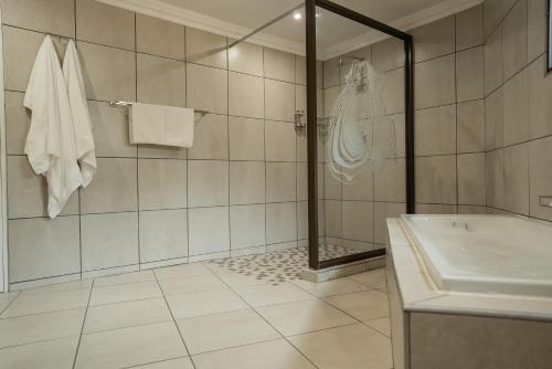 a bathroom with a shower and a tub and a sink at Tshukudu Game Lodge in Hoedspruit