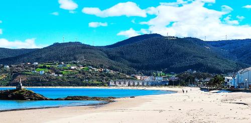 a beach with people walking on the sand and mountains at Apartamentos Minas de Silvarosa in Viveiro